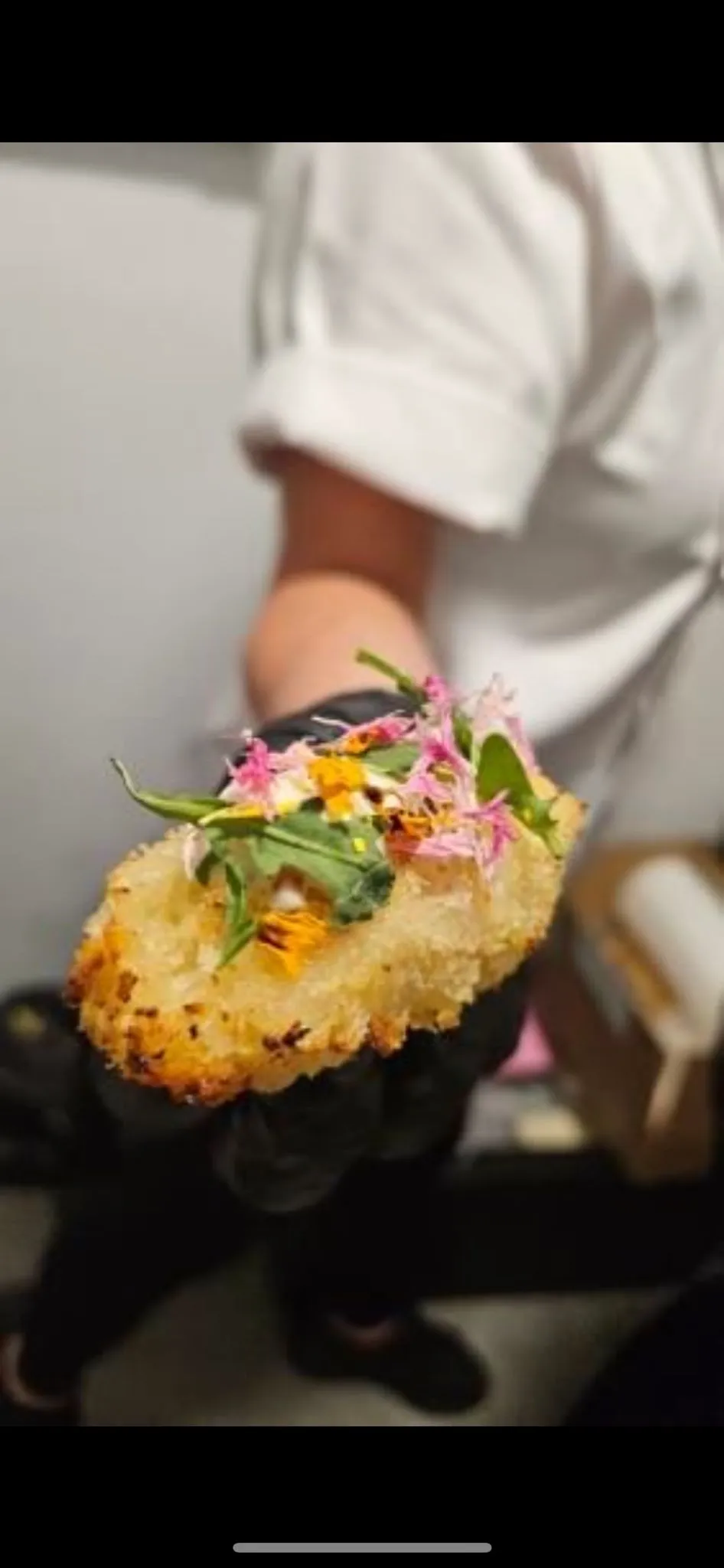 Close up of a chef's hand presenting a delicate canapé